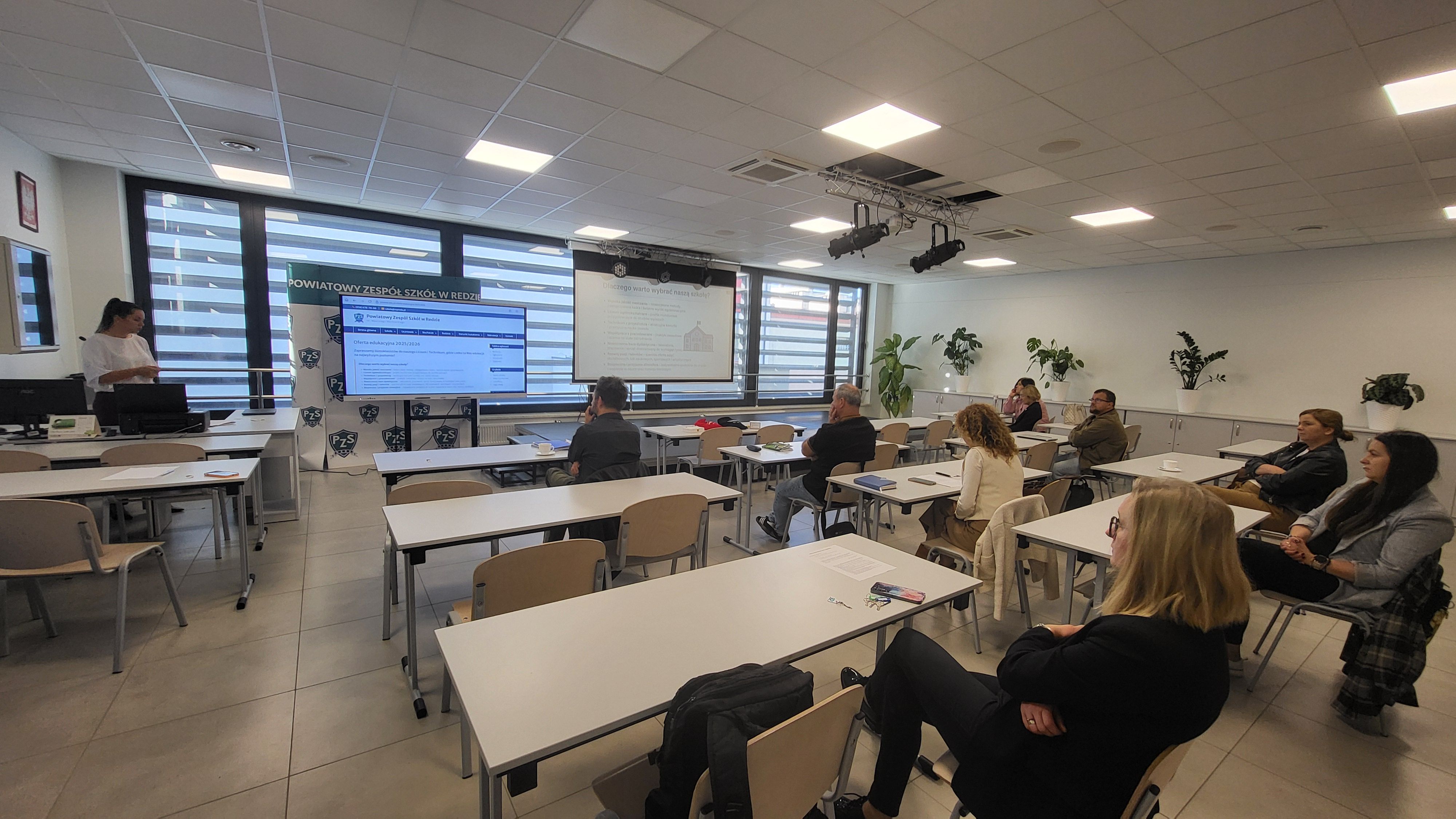 Widok na salę wykładową z wyświetlaną prezentacją.