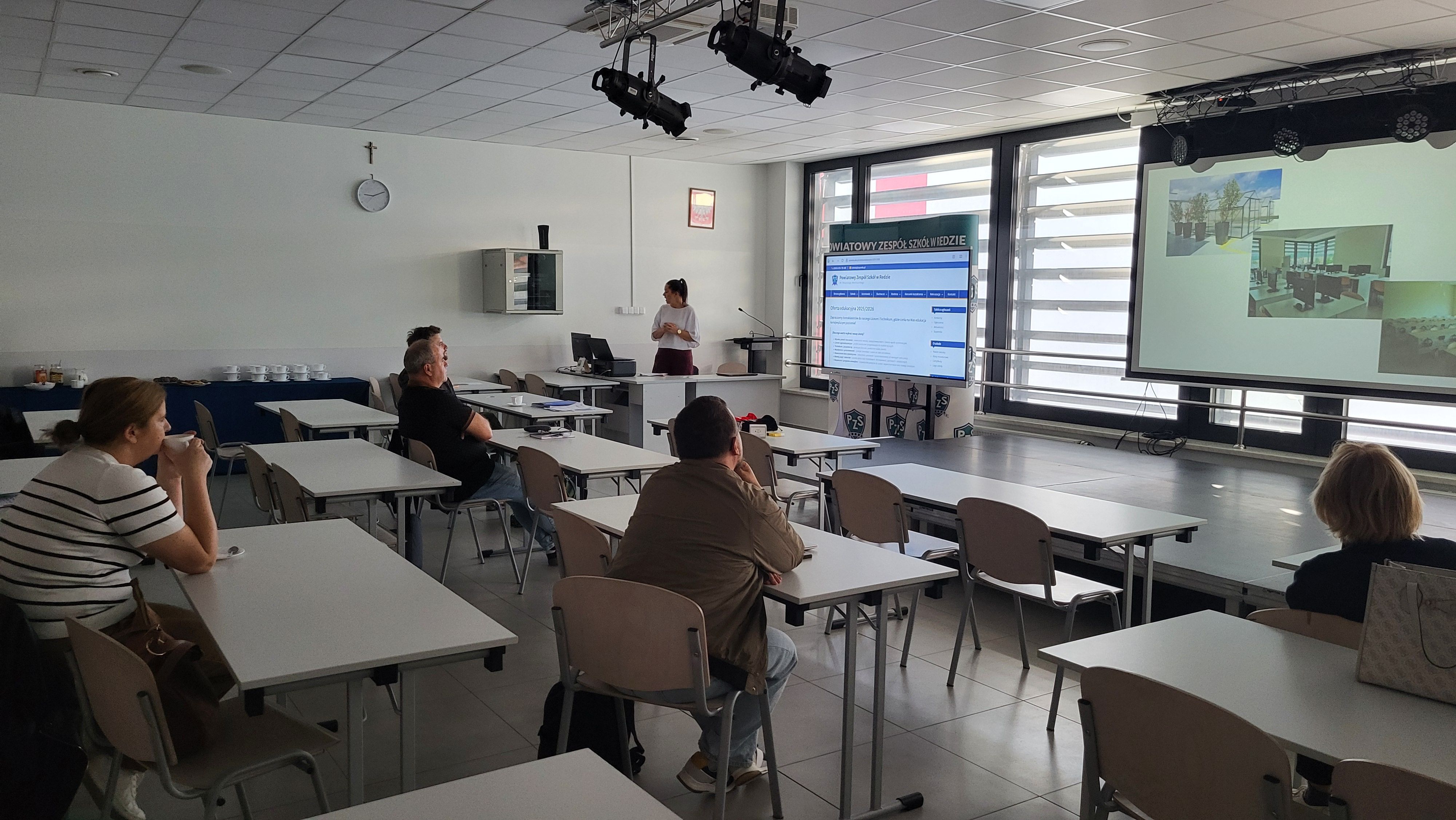 Widok na salę wykładową z wyświetlaną prezentacją.