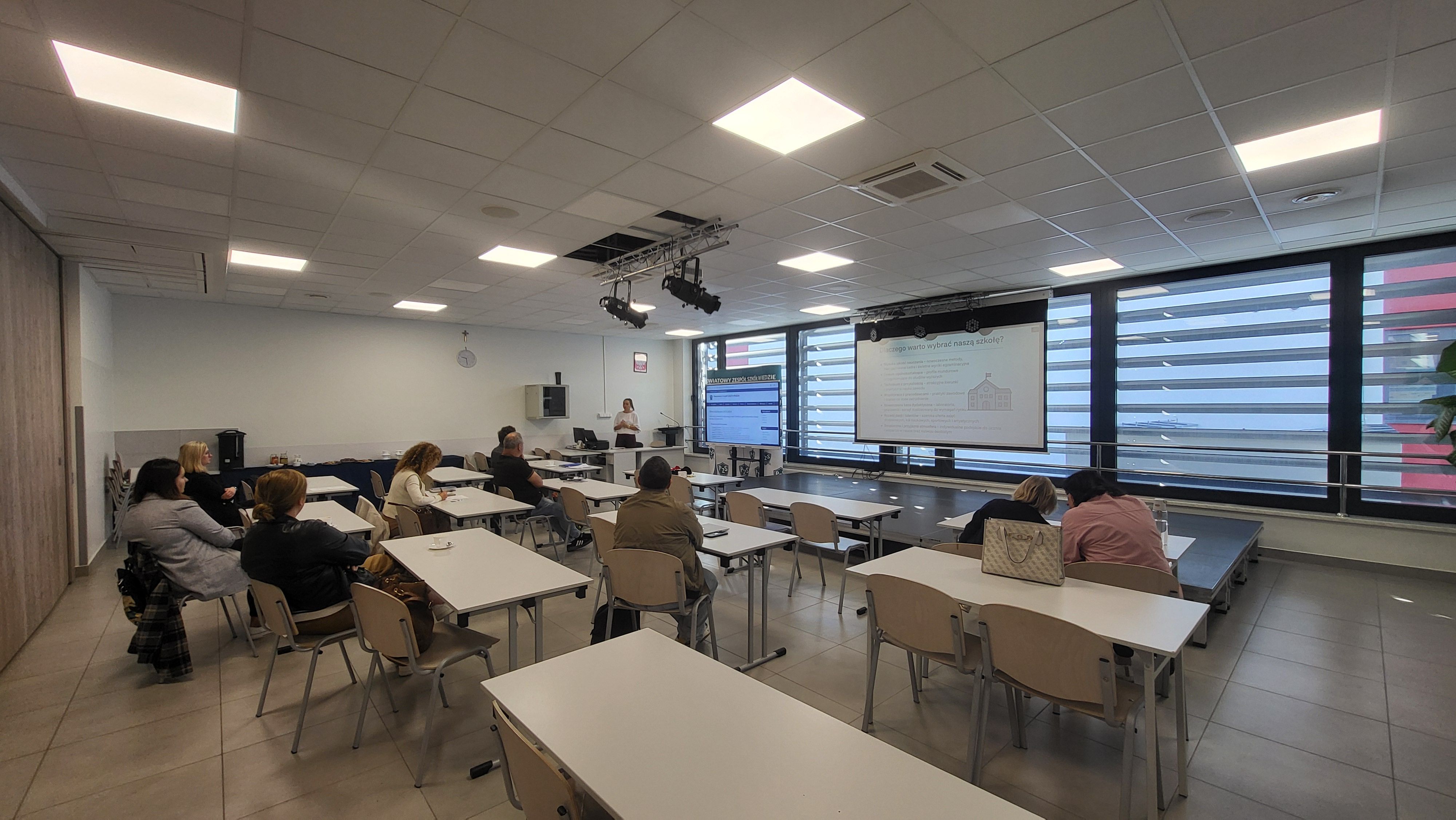 Widok na salę wykładową z wyświetlaną prezentacją.